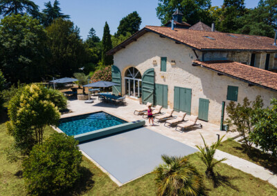 Sequoia Vue aérienne d’une maison en pierre avec piscine équipée d’une couverture Coverseal grise, intégrée harmonieusement dans la terrasse en pierre claire.